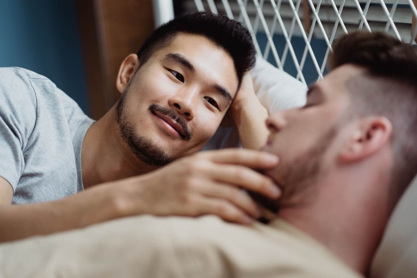 Close-up of two men in a tender indoor moment, one gently touching the other's chin