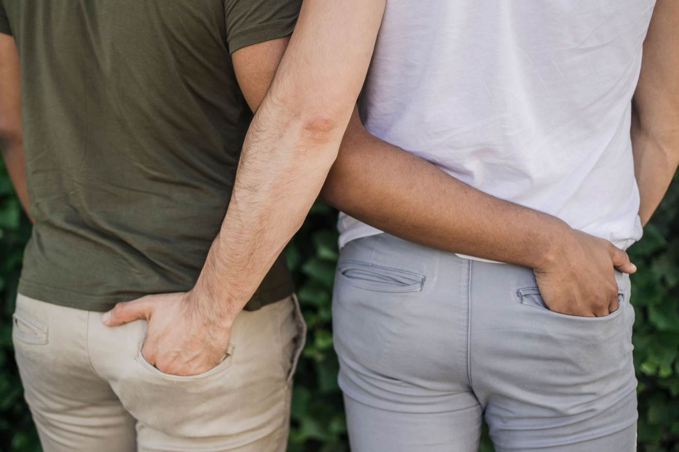 Two men standing close with arms around each other's waists